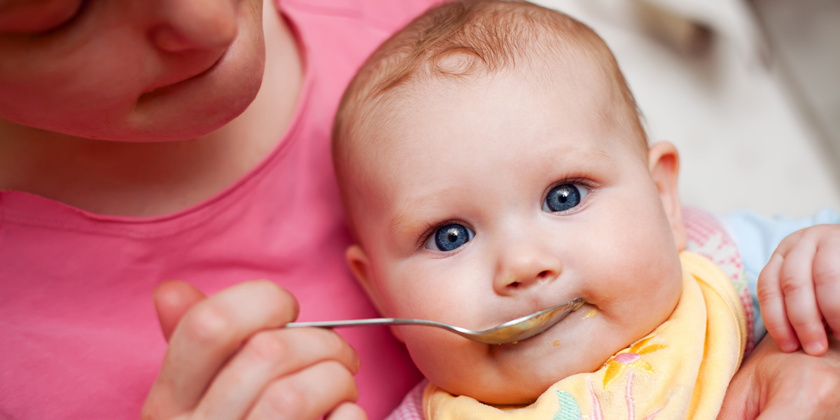 Mother feeding baby food to baby